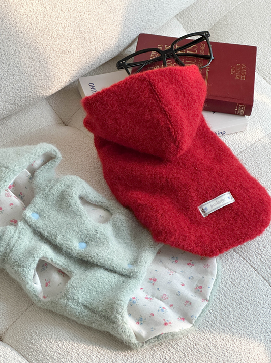 Red and green fuzzy hooded dog vest flat lay showing color options and cotton lining