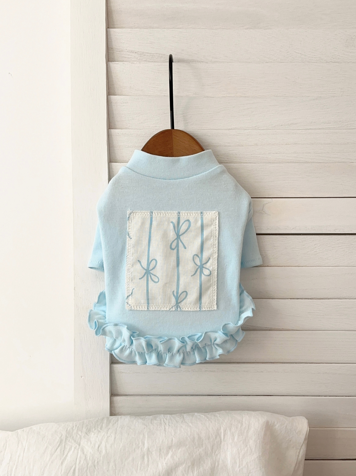 Front view of blue ruffle pet shirt with floral patch